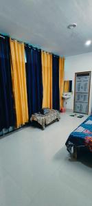 um quarto com cortinas coloridas, uma cama e uma mesa em Advik cottege em Rāmnagar