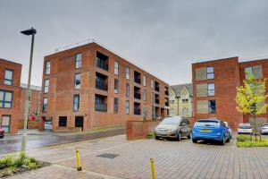 two cars parked in a parking lot in front of a brick building at Lovely Flat In Kiln Close With Free Parking in Gloucester