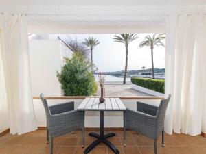 una mesa y sillas en un balcón con palmeras en Villa Gavines down, en S'Algar