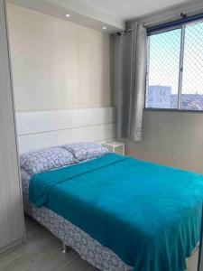 a bedroom with a bed with a blue blanket at Apto Lindo/Aconchegante perto da UEL/bares/ centro in Londrina