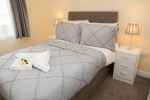 um quarto com uma cama com um edredão cinzento e almofadas em White Jasmine In Stroud em Stroud