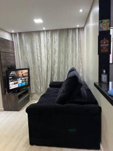 a black couch in a living room with a television at Apto Lindo/Aconchegante perto da UEL/bares/ centro in Londrina