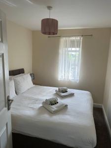 a bedroom with a white bed with towels on it at Yellow Sunflowers Flat In Stroud in Stroud