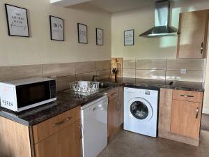 a kitchen with a washing machine and a microwave at Yellow Sunflowers Flat In Stroud in Stroud +2 photos