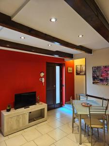 een woonkamer met een televisie en een tafel met stoelen bij Fiore rosso in Stresa