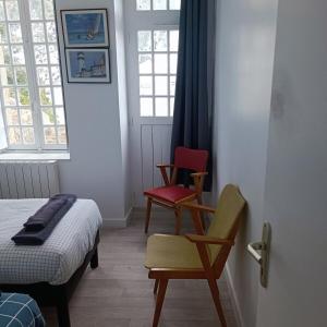 Chez Adèle في جبل القديس ميشيل: غرفة نوم بها كرسيين وسرير ونوافذ