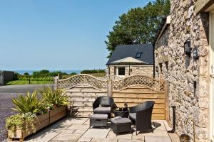 a patio with two chairs and a fence at Ewe Bach Cottage in Llanasa