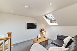 un salon avec un canapé et une télévision dans l'établissement Ewe Bach Cottage, à Llanasa