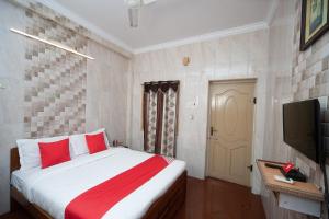 a bedroom with a bed with red pillows and a television at Flagship 35443 Kls Residency in Chennai