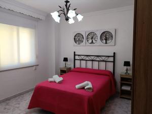 a bedroom with a red bed with two towels on it at Apartamento Candari Playa en Cadiz in Cádiz