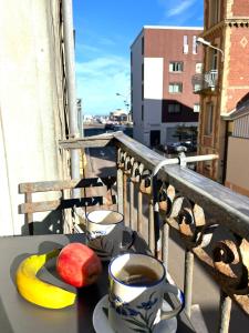een tafel met een kopje koffie en fruit op een balkon bij LES BAIGNEUSES in Dieppe