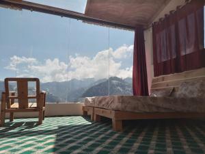 a bedroom with a bed and a chair in front of a window at Stargazing Glass Lodge Himachal Pradesh Thachi in Mandi