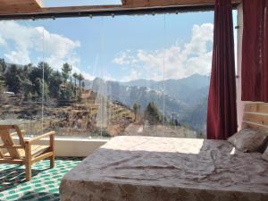a bedroom with a large window with a mountain view at Stargazing Glass Lodge Himachal Pradesh Thachi in Mandi