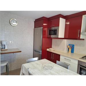 a kitchen with red cabinets and a table with chairs at Meraki in Finisterre +16 photos