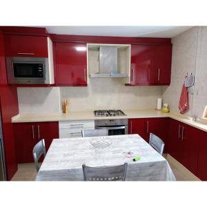 a kitchen with red cabinets and a table with chairs at Meraki in Finisterre