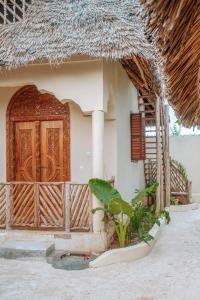 a house with a wooden door and a porch at Marvelous Zanzibar in Jambiani