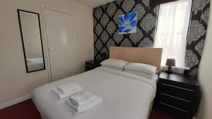 um quarto com uma cama branca e toalhas em The Langtry Hotel em Clacton-on-Sea