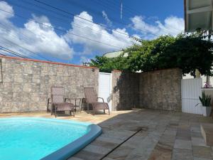 einen Pool im Hinterhof mit zwei Stühlen und einem Tisch in der Unterkunft Blumen Espaço "piscina privativa' in Blumenau