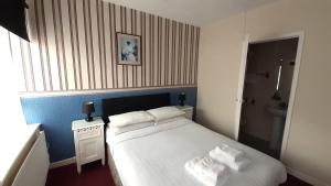 Un dormitorio con una cama blanca con toallas. en The Langtry Hotel, en Clacton-on-Sea