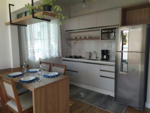 eine Küche mit einem Tisch und einem Kühlschrank aus Edelstahl in der Unterkunft Blumen Espaço "piscina privativa' in Blumenau