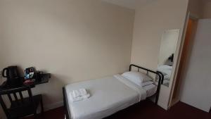 a small bedroom with a bed and a mirror at The Langtry Hotel in Clacton-on-Sea