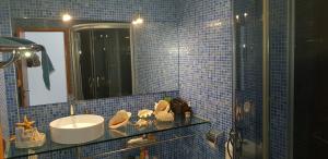 La salle de bains est pourvue de carrelage bleu, d'un lavabo et d'un miroir. dans l'établissement Casa Melfer, à Sesimbra