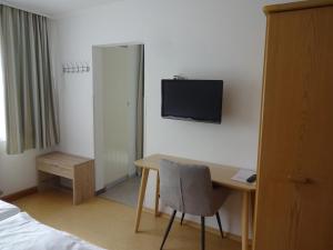 a hotel room with a desk and a television on the wall at Gästehaus Regina in Bad Füssing