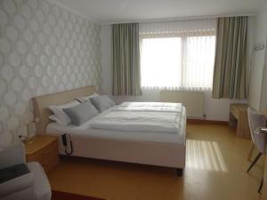 um quarto com uma cama branca e uma janela em Gästehaus Regina em Bad Füssing