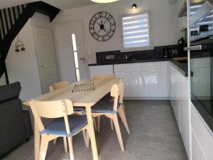a table and chairs in a kitchen with a clock on the wall at Le temps d'une pause in Villes-sur-Auzon +6 photos
