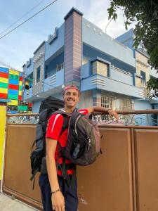un homme avec un sac à dos debout devant un bâtiment dans l'établissement Countryside inn, à Tiruvankod