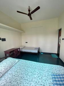 a bedroom with two beds and a ceiling fan at Countryside inn in Tiruvankod