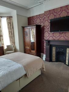 a bedroom with a bed and a flat screen tv at Branstone Guest House in Llandudno