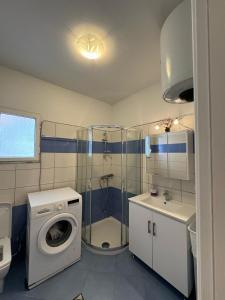 a bathroom with a shower and a washing machine at Mimosa Luxury Apartment in Sarandë +25 photos