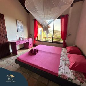 a bedroom with a large pink bed with a window at La Villa de Petite Anse - Piscine in Les Anses-dʼArlets
