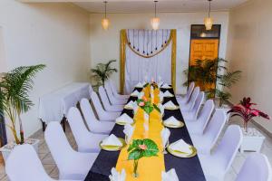 a dining room with a long table and white chairs at One Click Hotel in Kigali