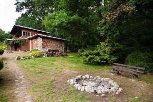 a building with a bench and a stone circle in the yard at Basen Przesieka - drewniany dom z dużym stawem kąpielowym in Przesieka