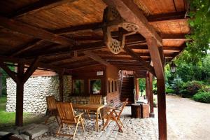 a patio with a table and chairs under a wooden roof at Basen Przesieka - drewniany dom z dużym stawem kąpielowym in Przesieka