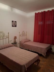2 camas en una habitación con cortinas rojas en Chalet Piscina Privada Urbanización Roche Viejo, en Conil de la Frontera