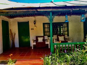 a porch of a house with green doors and chairs at Back o' the Moon Holiday cottage in Hogsback