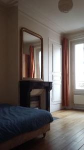 1 dormitorio con espejo, 1 cama y chimenea en Large and cosy, Paris-Ouest, en Levallois-Perret