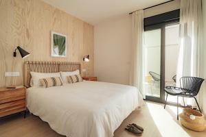 a bedroom with a large white bed and a chair at Los Olivos Apartments by Olala Homes in Seville
