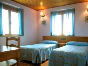 ein Zimmer mit zwei Betten und einem Tisch und Fenstern in der Unterkunft Casa Rural Roblegordo in Rabanera del Pinar