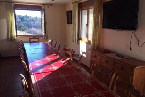 einen Esstisch mit Stühlen und einen Flachbild-TV in der Unterkunft Casa Rural Roblegordo in Rabanera del Pinar