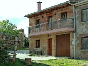 Casa de ladrillo con puerta de madera y balcón en Casa Rural Los Roblones, en Rabanera del Pinar