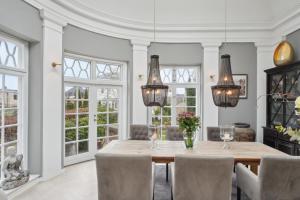 a dining room with a table and chairs and windows at Luksuriøs 270 m2 - 2BR Strandvilla m.Havudsigt in Hellerup