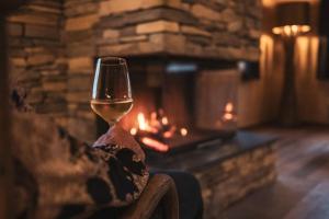 a glass of wine sitting in front of a fireplace at Antons Exklusives Landgut in Oberstaufen