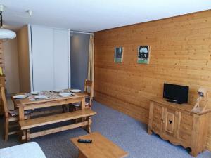 Cette chambre est dotée d'un mur en bois, d'une table et d'une télévision. dans l'établissement Le 3300 - 20 - Appart expo sud - 6 pers, à Les Deux Alpes
