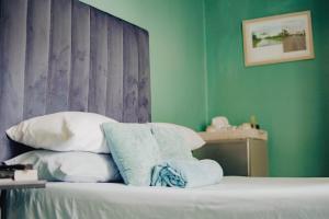 a bedroom with green walls and a bed with pillows at Kate's Nest Guesthouse in Windhoek