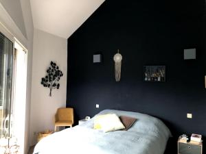 - une chambre avec un lit et un mur noir dans l'établissement Maison au pied des alpes, à Crolles