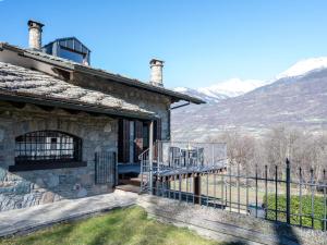 フェーニスにあるApartment Maison Pro de Solari-2 by Interhomeのバルコニー付きの石造りの家で、山々を背景に眺めることができます。